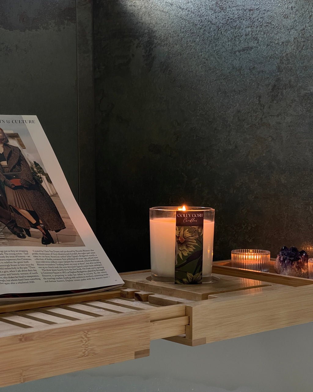Bath tray with candles and a magazine on a dark background