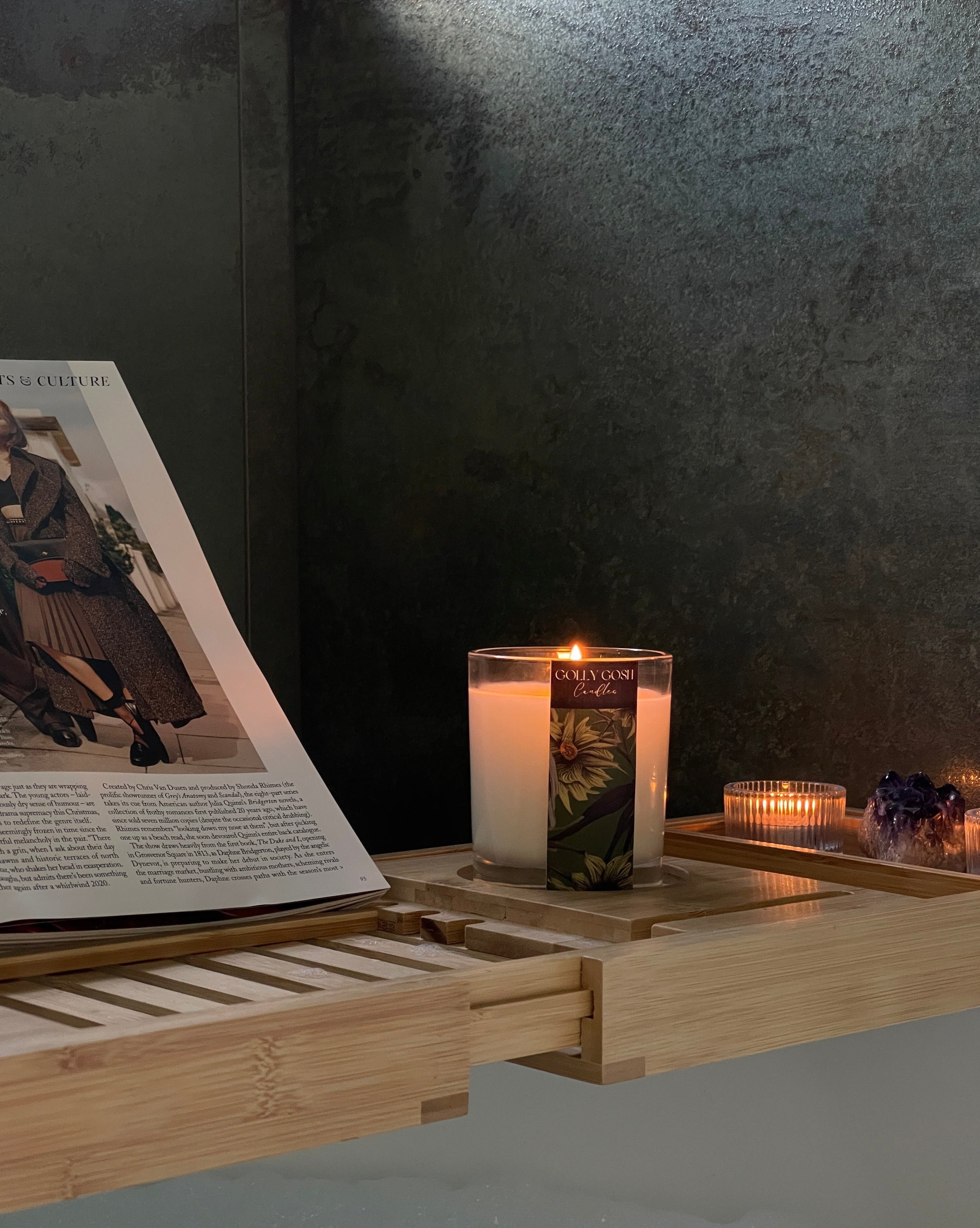 Bath tray with candles and a magazine on a dark background